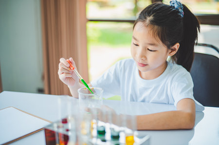 little scientist looking through a microscope and test tubes filled with chemicals for learning about science and experiments.の写真素材