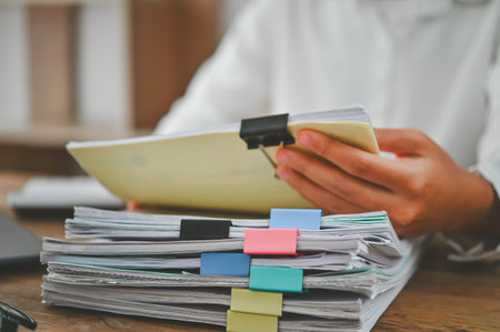 A person is holding a stack of papers with colorful clips on them