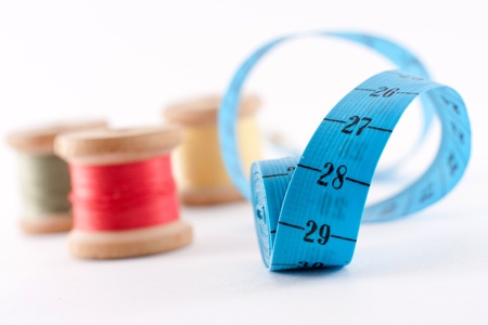 colored bobbin threads and blue yardstick on wite