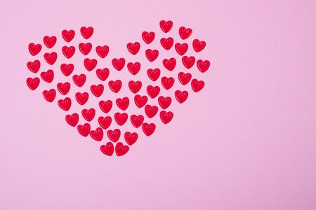 Little red hearts shape big one on pink background