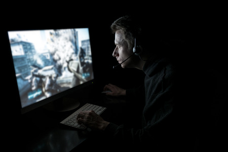 Young man playing computer games in dark room