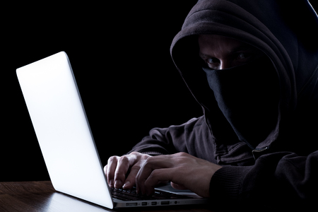 Anonymous hacker with laptop in the dark. Cyber security conceptの写真素材