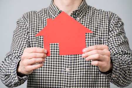 Man holding red cardboard model of house. Concept for mortgage loan for homeの写真素材
