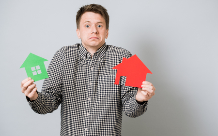 Men holding green and red houses made from cardboard. Idea for complexity of choiceの写真素材