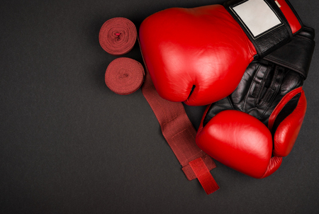 Pairs of red leather boxing gloves and hand wraps on black surfaceの写真素材