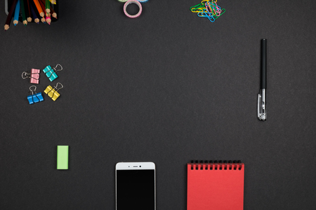 Top view of office supplies with smartphone on surface of dark table. Workplace conceptの写真素材