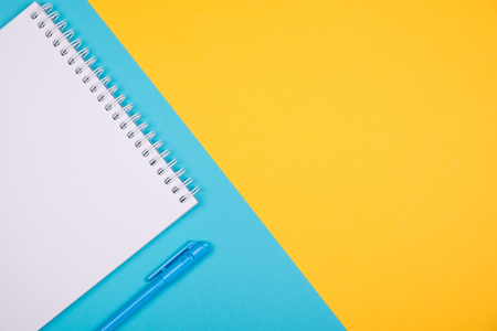 Empty notepad with blue pen on contrast yellow and blue backgroundの写真素材
