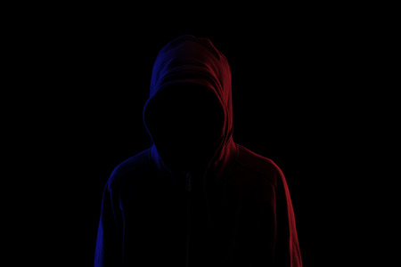 Man in hoodie with unrecognizable face in the darkの写真素材