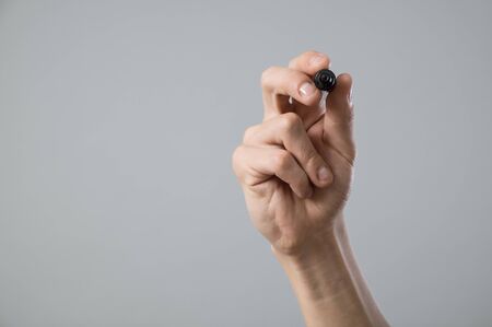 Young man hand with pen writing on virtual screen isolated on greyの写真素材