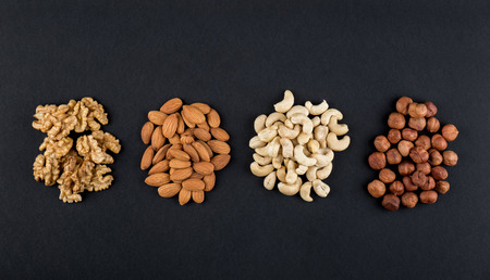 Walnuts, almonds, cashews and hazelnuts isolated on black with copy space. Raw food ingredients top...