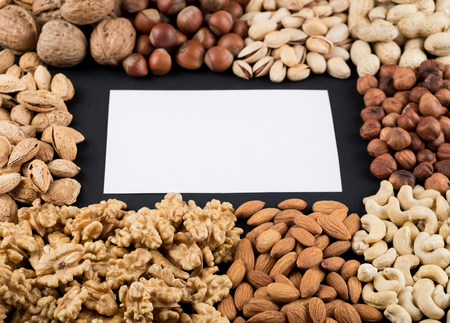 Walnuts, peanuts, pistachios, almonds, cashews and hazelnuts isolated on black with copy space. Raw...