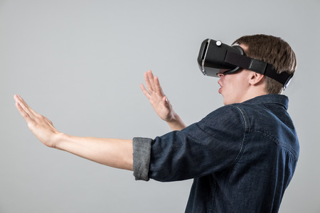 Man using virtual reality goggles on grey background