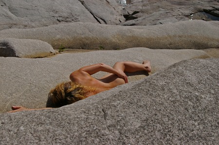 A sexy nude woman model posing outdoors on a rockの写真素材