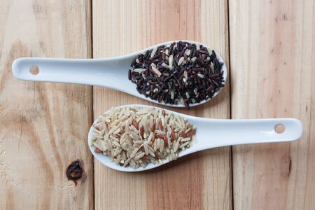 Brown rice or riceberry  in spoon on wood backgroundの写真素材