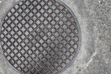 Drain cap on the concrete of sewer cover on the walk way old strong steel iron and grungy.の写真素材
