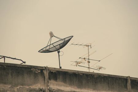 Satellite dish on roof of old building, vintage color tone.の写真素材