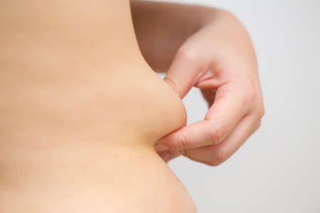 Woman pinching fat from her waistの写真素材