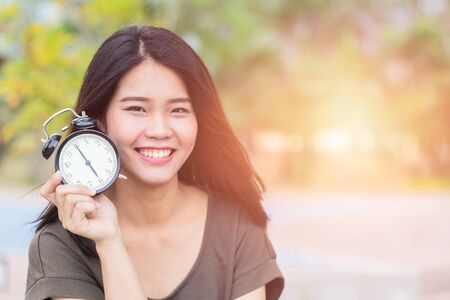 Thai Asian women show and point her face aside with clock, Time reverse back to baby skin concept.の写真素材