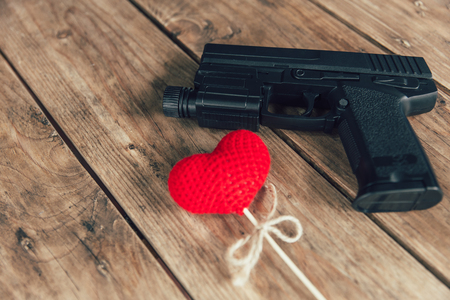 pistol gun and love red heart on wood backgroundの写真素材