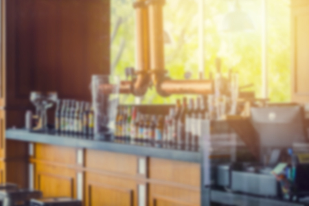 blur luxury counter bar beer with draft beer tube and many brand of beer glass bottle in pub at morning day close for background.の写真素材