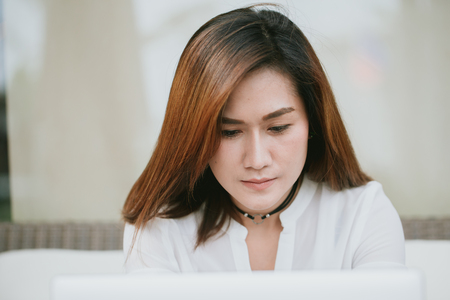 asian women professional work hard looking down at laptop screen in working office.の写真素材