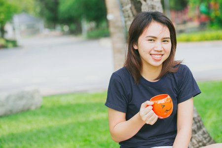 asian teen handle smile mug in the green park. happy drink coffee concept.の写真素材