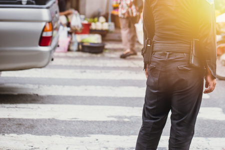 Thailand city officer security on duty in official clothes with radio looking people cross the road...