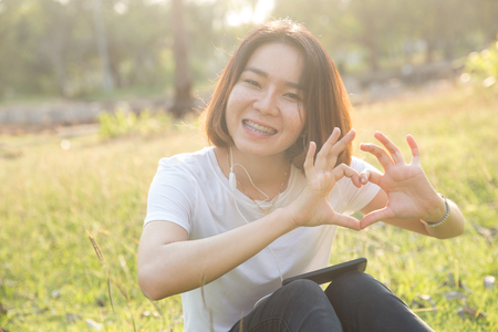 Cute Thai asian girl love heart shape with her hands in sunshine.の写真素材