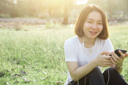 Short hair Asian teen girl enjoy with music from mobile phone with small talk everyday conceptの写真素材