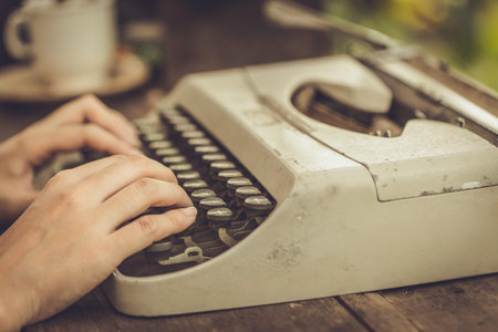 Closeup women hand using old typewriter vintage color tone