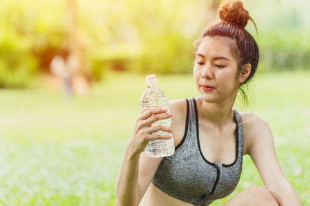 Asian sport teen look at drinking water bottle while outdoor activity selective focus at the drink water bottleの写真素材