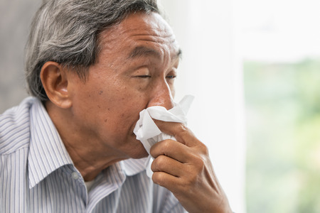 Asian Old man elder get sick wipe the nose snot from flu and runny nose when season change.の写真素材