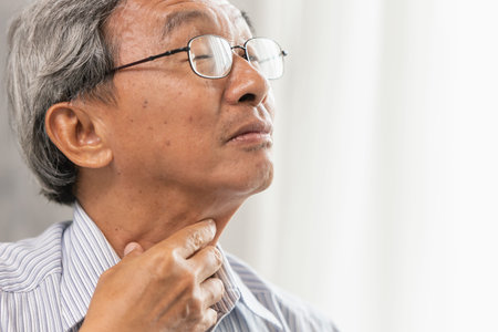 Asian elder old man Sore throat irritation and have a phlegm hand touching neck.