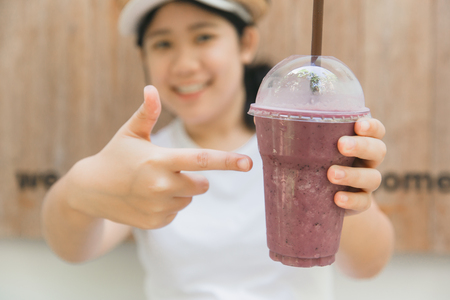 cute teen hand holding healthy drink in summer fruity blueberry smoothieの写真素材