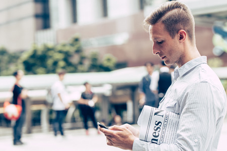 businessman reading business news update in smartphone instead read from newspaperの写真素材