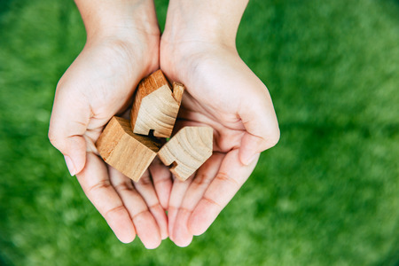 hand giving home on green background for good community concept.の写真素材