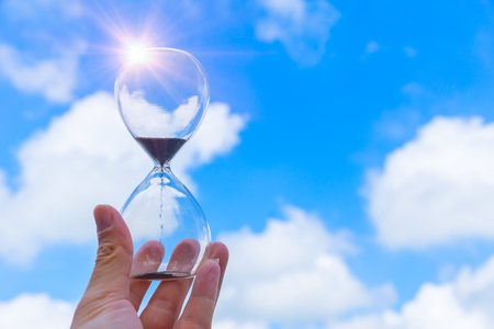 Hourglass Sand Timer Clock time hand holding with blue sky cloud background.の写真素材
