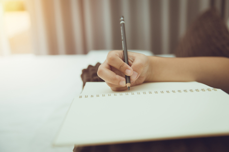 student hand hold pencil writing note blank book vintage colortoneの写真素材