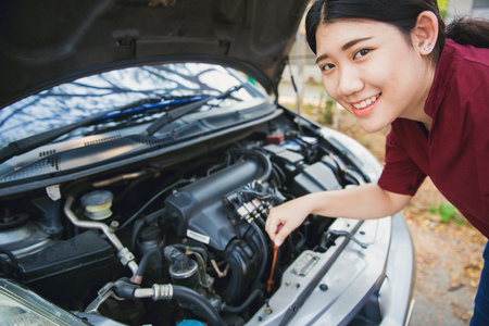 Teen girl open car hood check engine oil level of vehicle before driving travel weekend.の写真素材