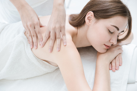 woman lying relax eyes close spa massage therapist massaging her shoulders white clean toneの写真素材