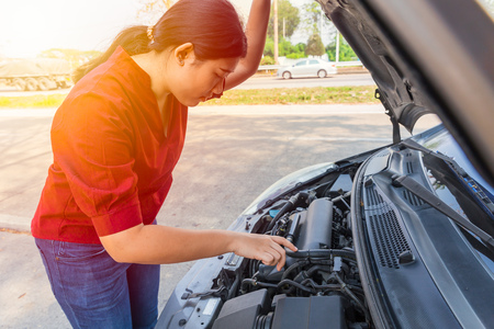 Asian teen girl open car hood to checking engine oil fix breakdown problem.の写真素材