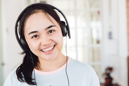 Asian cute young teen smiling with headphone enjoy music looking camera.の写真素材