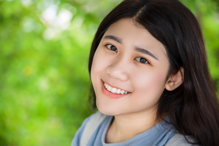 cute Asian healthy plump teen girl smile wth beautiful blur green nature backgroundの写真素材