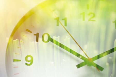 Times clock face overlay with green grass nature background. time to saving environment ecology conceptの写真素材