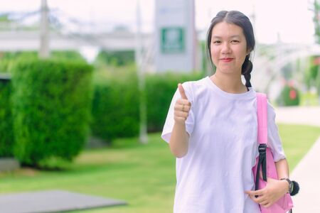 Asian young girl teen smiling with thumb up outdoor bright dayの写真素材