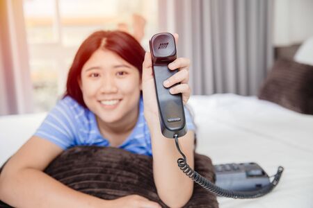Asian girl teen with landline phone call happy smile impressive with customer care support concept.の写真素材