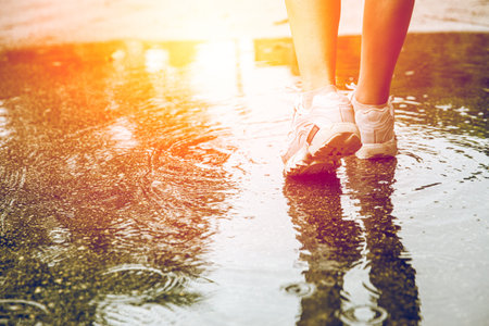 Closeup feet walking in water at the ground after rain for step over obstacles in life to next good...
