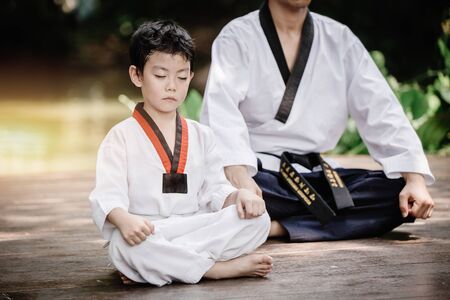 Fighter kid in Taekwondo uniform sitting concentration for training self defense body and mild.の写真素材
