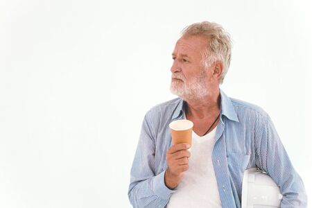 old man American Caucasian worker hand holding paper coffee cup wearing casual relax clothes looking away isolated on white background. Engineer Thinking or vision dreaming elderの写真素材