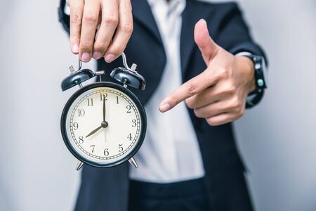 business people hand finger pointing at clock times at 8 o'clock, reminder time to do something or timing notice conceptの写真素材